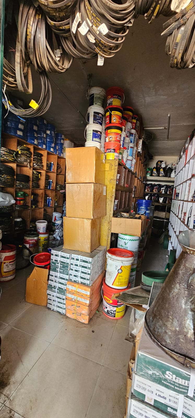 Stockroom aisle stacked with belts, buckets and welding consumables